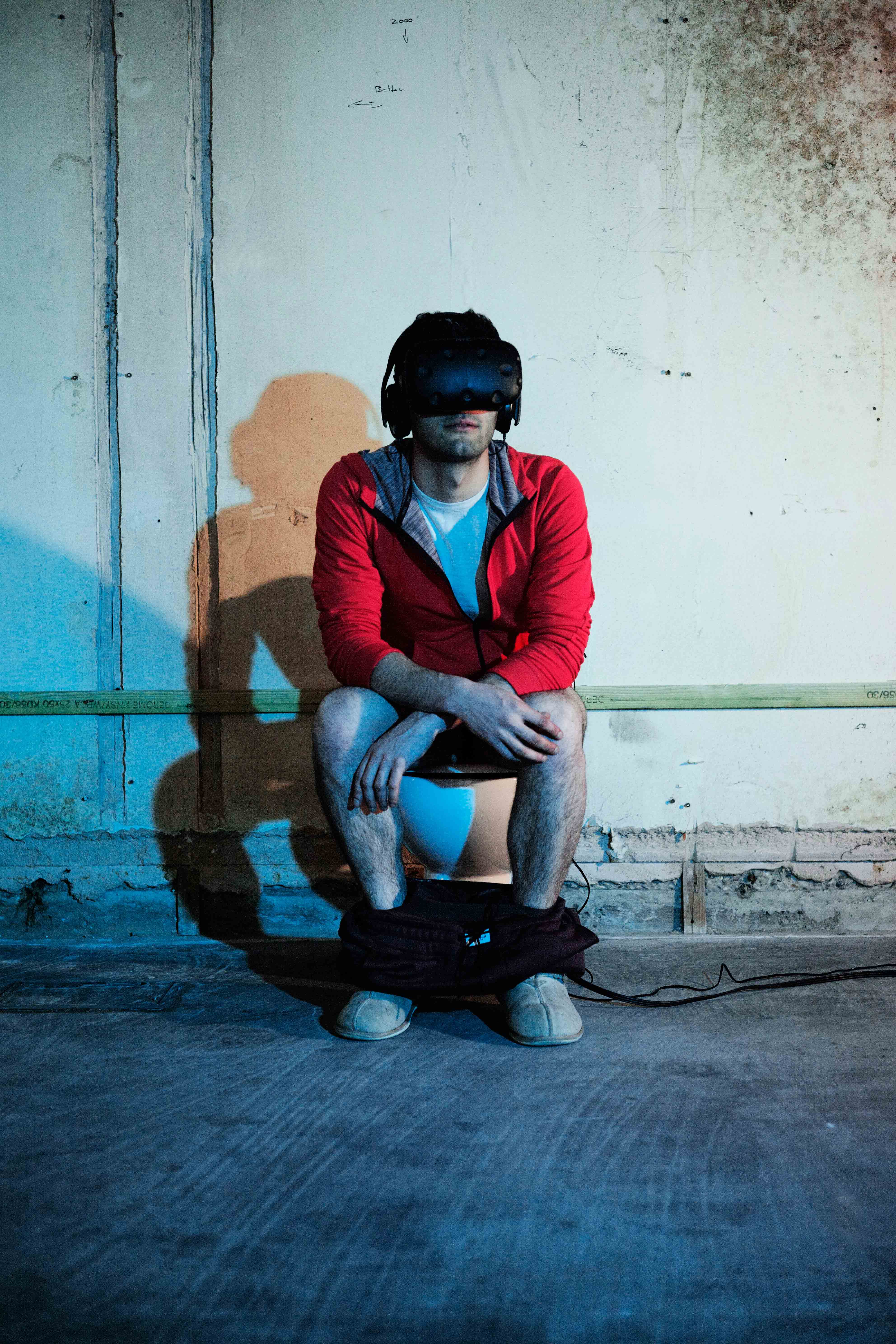 The artist wearing the VR headset whilst using the toilet.